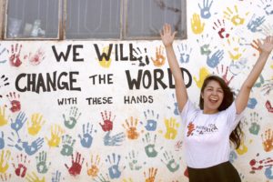 Samantha Mendoza with her hands up in front of a hand print wall