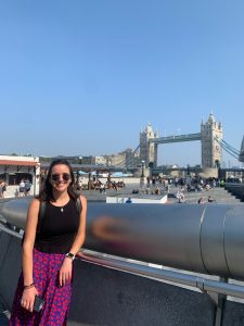 woman stands in front of blue sky and scenery from London