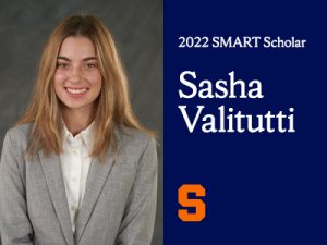 Headshot of a young woman smiling with long blonde hair and a gray business suit in front of a gray background. To the right is a blue rectangle with the words "2022 SMART Scholar Sasha Valitutti" and the Syracuse Orange "S" in the bottom left.