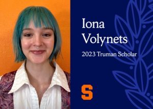 Woman smiles with blue hair in front of an orange background next to a blue text box that reads "Iona Volynets 2023 Truman Scholar"